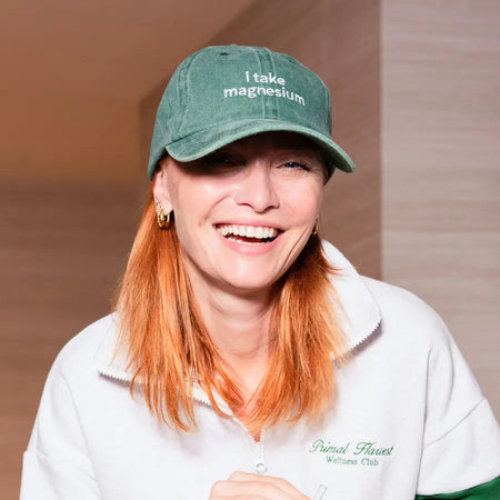 Woman wearing a green cap with 'I take magnesium' text.